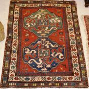 A Kashan rug, the central panel set with two geometric patterned medallions in blue and teal, on a