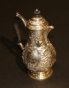 A Victorian silver hot water jug of baluster shaped form with all over floral and C-scroll