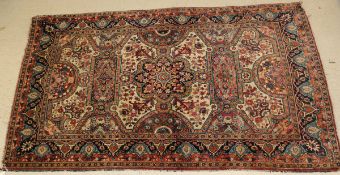 A fine Persian rug, the central panel set with floral decorated medallion on a cream and red