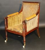 A Regency mahogany and caned bergere reading chair, the moulded frame with leather elbow rests,