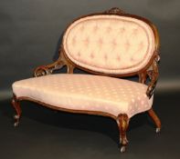 A late Victorian mahogany framed salon settee with oval buttoned back and carved show frame over a
