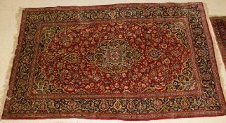 A Kashan rug, the central panel set with floral decorated medallion on a red ground with floral