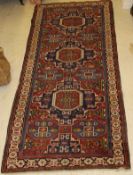 A Shirvan runner, the central panel set with three repeating geometric decorated medallions on a red