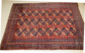 An Afghan carpet, the central panel set with three rows of repeating stylised elephant foot