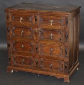 An oak chest in the 17th Century manner, the two piece top with moulded edge above four long