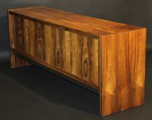 A 1970's rosewood veneered sideboard by Merrow Associates, the plain top above two sliding doors and