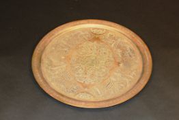 An Eastern brass charger with etched decoration, bearing silvered script, 65 cm diameter.