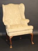 An 18th Century upholstered wing back scroll arm chair on four slender plain cabriole supports to