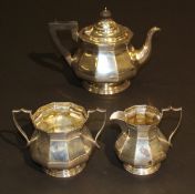 A George V silver three piece tea set of hexagonal bellied form raised on circular graduated feet