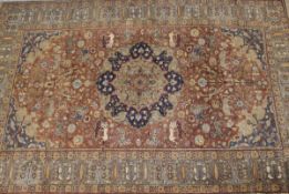 A Persian carpet, the central panel set with a floral decorated medallion on a brown ground with
