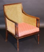 A mahogany and caned bergere armchair in the Regency taste, the frame with moulded decoration raised