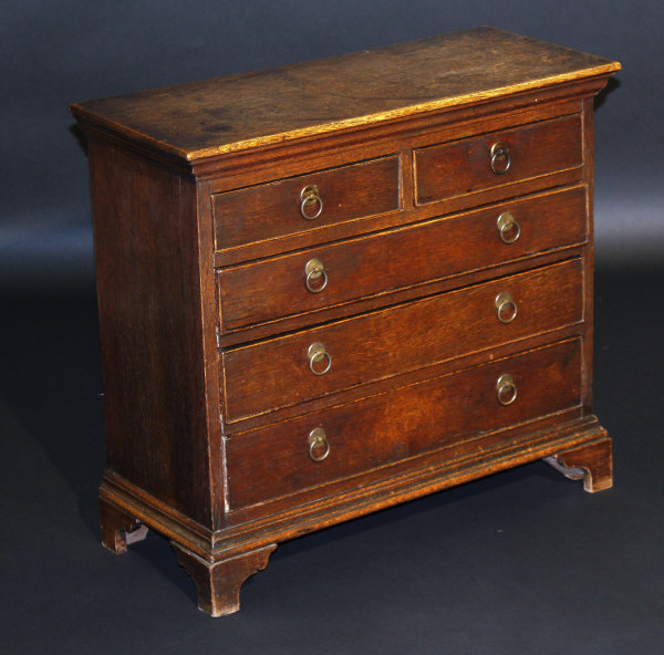 A 19th Century oak miniature chest of two short and three long graduated drawers on bracket feet,
