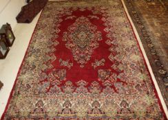 A Persian carpet, the central panel set with floral decorated medallion on a red ground decorated