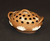 A 19th Century brown Jasper ware type pot-pourri of oval form decorated in relief with white