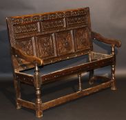 A circa 1700 oak settle, the carved back with lunette and foliate decoration flanked by notch carved