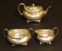 An Edwardian silver three piece tea set of oval bellied form with applied pie crust rim raised on