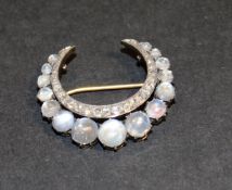 A Victorian closed crescent shaped brooch set with graduated circular cut cabochon moonstones and