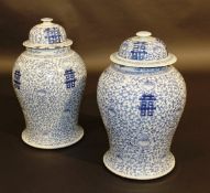 A pair of 19th Century Chinese blue and white baluster shaped marriage vases and covers with all-