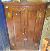 An 18th century oak hanging corner cupboard, the two fielded panelled doors enclosing a painted
