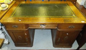An early 20th century oak kneehole desk with green leather insert top