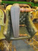 A green leather upholstered tub chair with buttoned back and arms, raised on reeded front legs,
