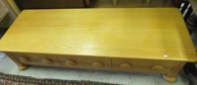 A low rectangular coffee table in veneered finish, with three short drawers to sides on bun feet,