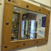 A rectangular pine framed mirror with beaten metal roundel decoration