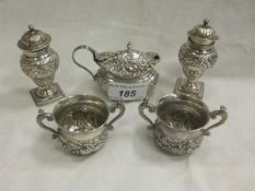 A pair of silver peppers of baluster shaped form with embossed floral decoration, together with a