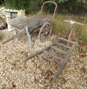 A vintage wooden hand cart with wooden wheel with a cast iron rim, together with a similar wooden
