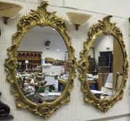 A pair of gilt framed oval wall mirrors with acanthus decoration in the Rococo taste   CONDITION