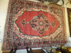 A Hamadan rug, the central floral medallion on a red chequered ground, within red, cream, blue and