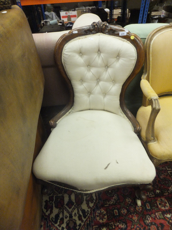 A Victorian carved walnut framed salon chair with buttoned back and cream upholstery