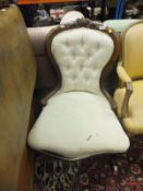 A Victorian carved walnut framed salon chair with buttoned back and cream upholstery