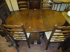 An oak drop-leaf dining table and a set of four rush seated ladder back dining chairs