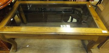 A rectangular walnut framed coffee table with glass top
