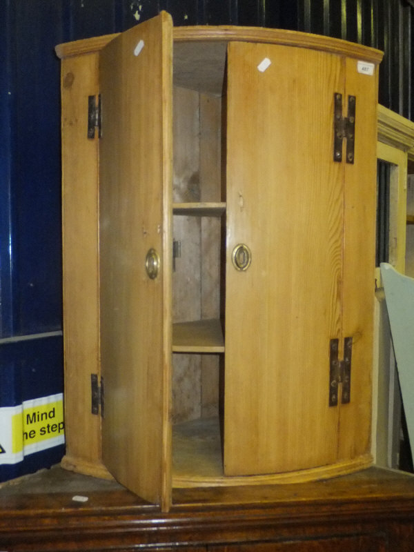A pine bow fronted two door corner cabinet