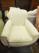 An early 20th Century armchair, raised on bun feet to castors, upholstered in cream damask fabric