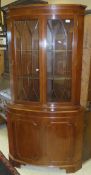 A yew wood corner display cabinet, the glazed top enclosing three shelves with two cupboard doors