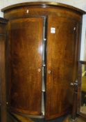 An early 19th Century mahogany and inlaid bow fronted two door hanging corner cupboard