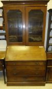 A late 19th Century bureau bookcase, the shaped cornice above two glazed doors opening to reveal