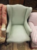 An early 20th Century wing back armchair, raised on cabriole front legs, upholstered in pale green