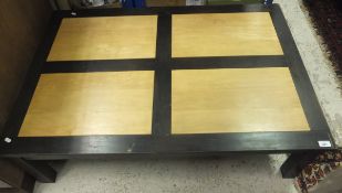 A rectangular coffee table with a maple top and black stained frame