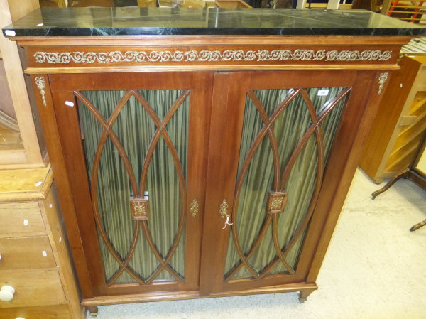 A mahogany two door cabinet, the glazed doors with green silk backing enclosing four shelves with