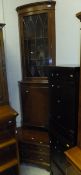 A yew wood corner display cabinet with glazed door enclosing three shelves and enclosed cupboard