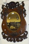 An oak shield shaped wall mirror with carved acanthus and ribbon decoration and carved shell
