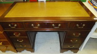 A reproduction mahogany kneehole desk with gilt embossed insert top and brass handles   CONDITION