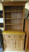 A pine dresser with four open shelves above two drawers and two cupboard doors