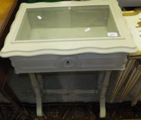 A pale green painted bijouterie cabinet / table with hinged glazed top, raised on baluster turned