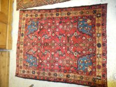 A Persian rug, the red central ground with all-over repeating medallions in blue, green, pink and