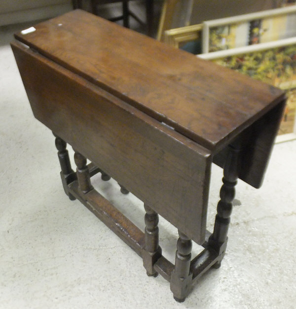 An oak slim drop leaf gate leg dining table in the 17th century manner on turned supports